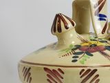a small vase with a bird on it on a table