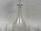 a glass decanter and four glasses on a table