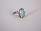 a close up of a ring on a white surface with a blue stone