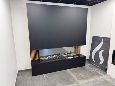 une cheminée dans un coin d'une pièce où est accroché un tableau au mur