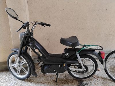 une petite moto noire garée contre un mur