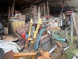 a pile of junk in a garage with a ladder and other items