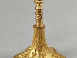 a gold plated candle holder with a cross on top of it