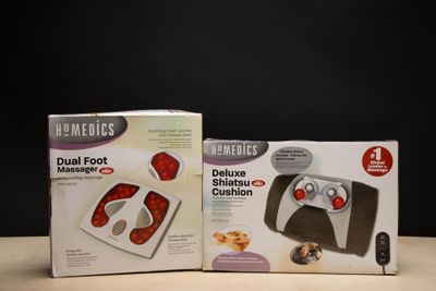 deux boîtes contenant un appareil de massage double pour les pieds Homedics posées sur une table