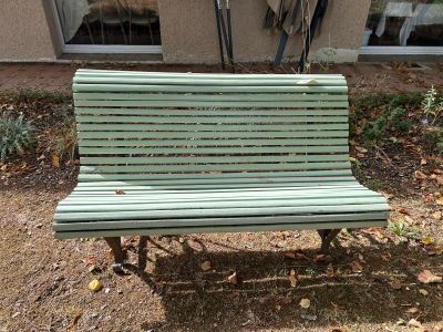 un banc vert situé devant un immeuble