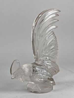 une sculpture en verre transparent représentant un oiseau, posée sur une table