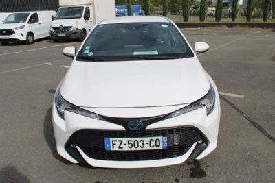 une voiture blanche garée sur un parking, avec d'autres voitures en arrière-plan