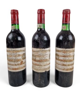 trois bouteilles de vin rouge sont posées les unes à côté des autres sur une surface blanche