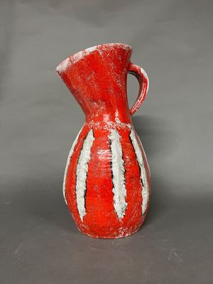 un vase rouge et blanc posé sur une surface grise