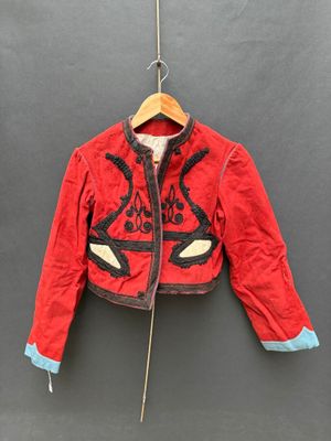 une veste rouge suspendue à un cintre accroché au mur