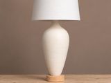 une lampe de table blanche posée sur une table en bois, près d'un mur marron