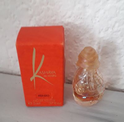 a small bottle of perfume sitting next to a red box