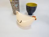 deux vases et un poulet en céramique posés sur une table