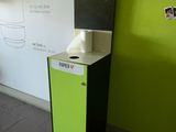 une poubelle verte et noire près d'un mur blanc