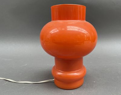 une lampe de table orange avec un cordon blanc posée sur une surface grise