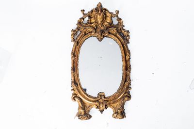 un miroir doré accroché au mur, à côté d'un mur blanc