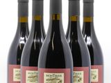 quatre bouteilles de vin rouge sont alignées sur une surface blanche