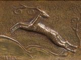 une plaque en bronze représentant un cerf bondissant dans les airs