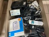 une boîte remplie de téléphones portables et de télécommandes posée par terre