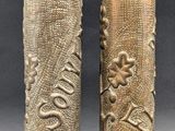 pair of brass vases with floral designs on them on a gray background