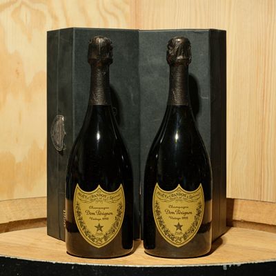 two bottles of champagne sitting on top of a wooden barrel