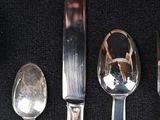 five silver spoons and two silver spoons on a black cloth