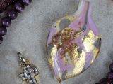 purple and gold necklaces and a cross on a marble surface