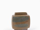 un petit vase marron et vert posé sur une surface blanche