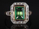 un gros plan d'une bague en tourmaline verte posée sur une surface noire