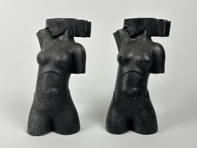 une paire de sculptures noires représentant des torses féminins sur fond blanc
