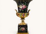 a black vase with flowers on it on a stand