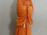 an orange jade buddha figurine on a white surface