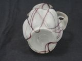 a white and red vase on a black surface