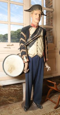 a statue of a man in a uniform with a drum in front of a window