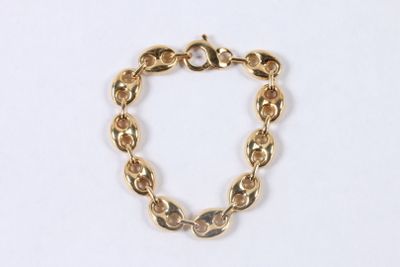 gros plan d'un bracelet en chaîne en or sur une surface blanche