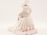 a white statue of a woman in a dress on a stand