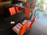 a black table with orange chairs and a black table with orange chairs