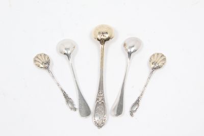 trois cuillères et deux cuillères en argent sur une surface blanche