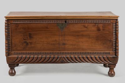 an old wooden chest with a carved top and legs