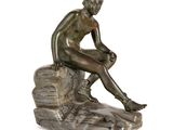 statue en bronze représentant un homme assis sur un rocher, les jambes croisées