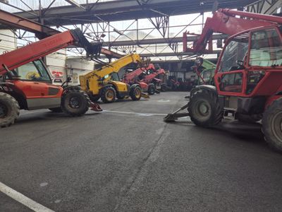 many different types of construction equipment parked in a warehouse