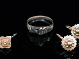 three rings and a pair of earrings sit on a black surface