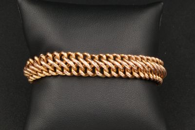 un bracelet plaqué or posé sur un coussin noir
