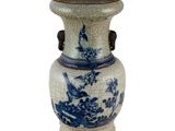 un vase bleu et blanc posé sur une surface blanche
