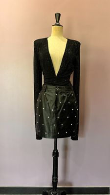 une robe noire posée sur un mannequin devant un mur rose