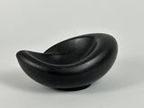 a black bowl that is sitting on a white surface