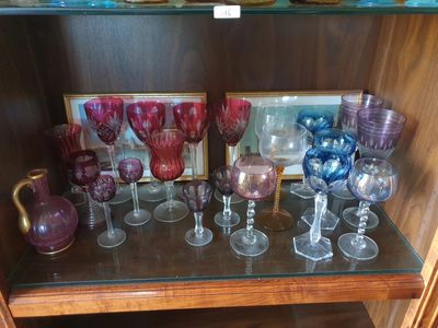 de nombreux verres de différentes couleurs posés sur une étagère dans un placard