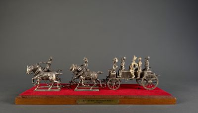 a silver figurine of a group of people riding in a horse drawn carriage