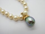 une image représentant un collier de perles muni d'un fermoir en or et d'une perle