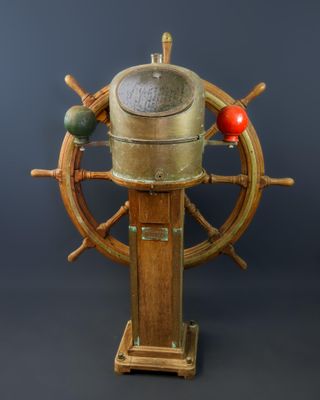 une barre de bateau en bois et en laiton surmontée d'une boule rouge